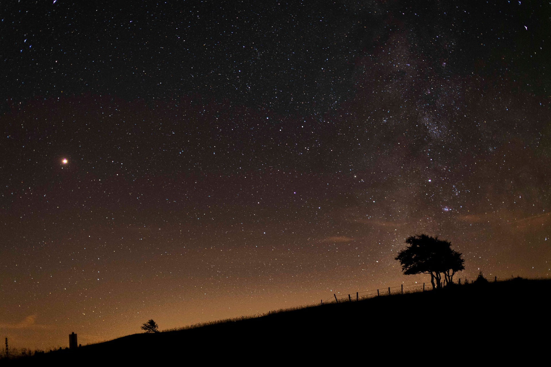 Ciel étoilé au-dessus d'une colline silhouettée